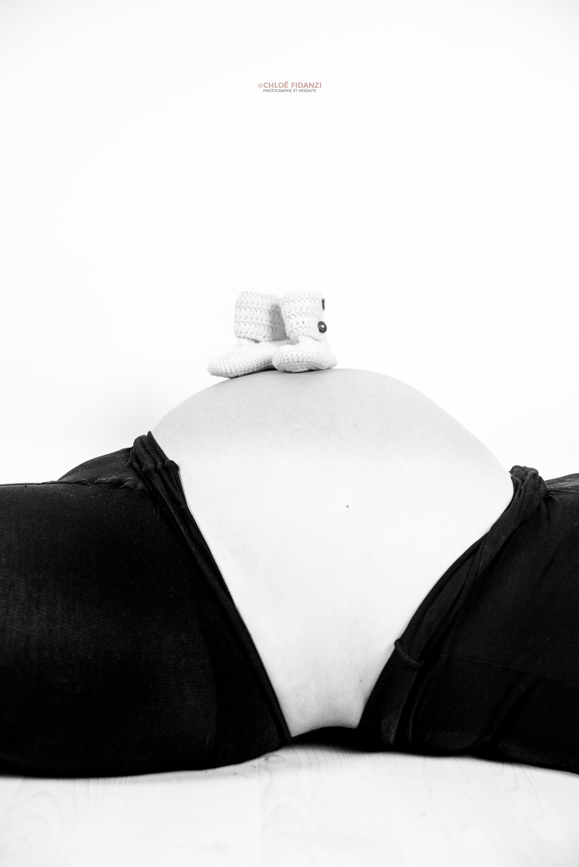 Chaussons de bébé posés sur le ventre rond de maman